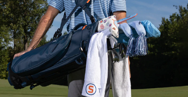 A golfer carries a STITCH Golf bag on a golf course.